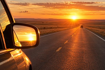 A driver travels toward bright low-angle sunlight on an Oklahoma roadway with traffic ahead.